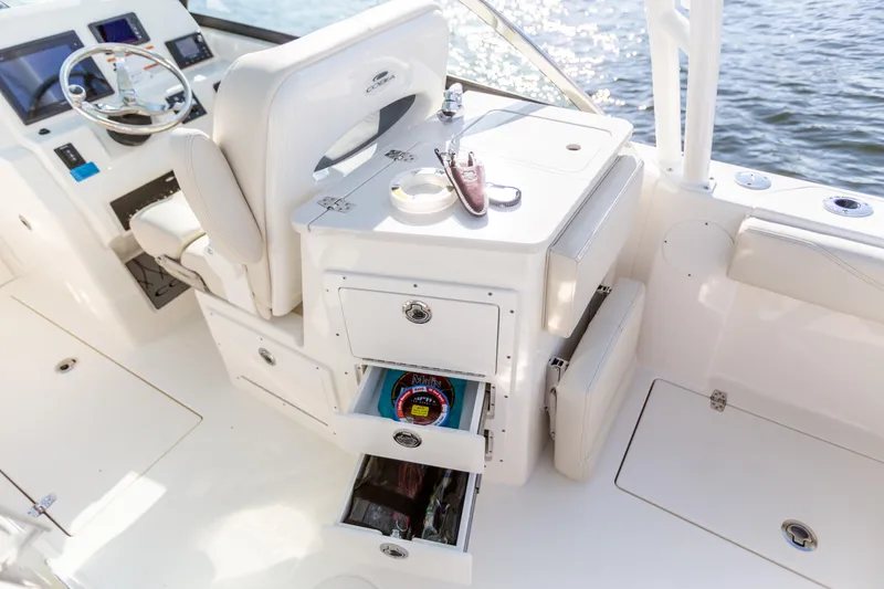 Slide: The Image of 2022 Cobia 240 DC boat interior with helm, storage drawers, and water view. - 42