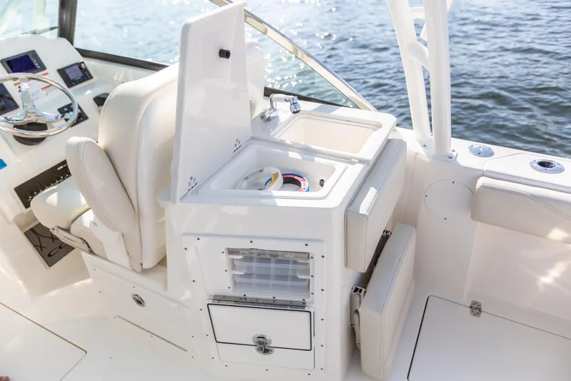 Slide: The Image of 2022 Cobia 240 DC boat interior with helm, sink, and storage compartments. - 43