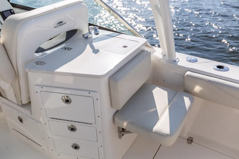 Slide: The Image of 2022 Cobia 240 DC boat interior with seating and storage, near water. - 44