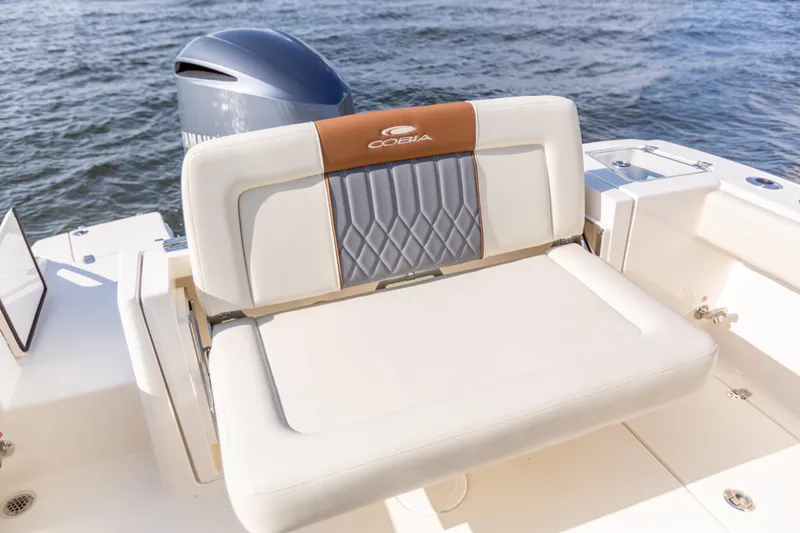 Slide: The Image of 2022 Cobia 240 DC boat with cushioned seating, ocean backdrop, and visible outboard motor. - 46