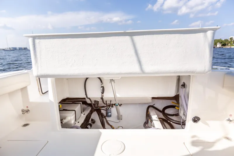 Slide: The Image of 2022 Cobia 240 DC boat storage compartment with open hatch, showing internal wiring and components. - 48