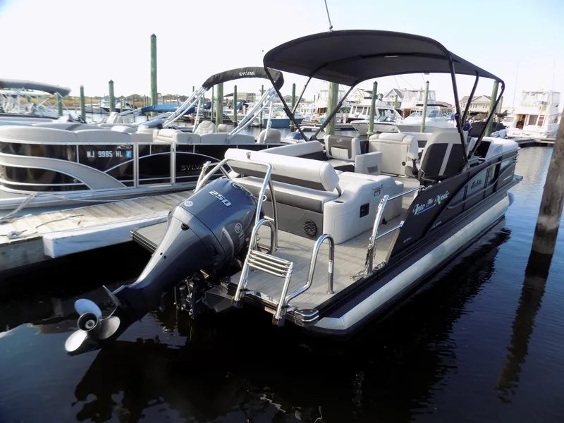Slide: The Image of 2021 Barletta Corsa 23U pontoon boat docked, featuring a sleek design and powerful outboard motor. - 2