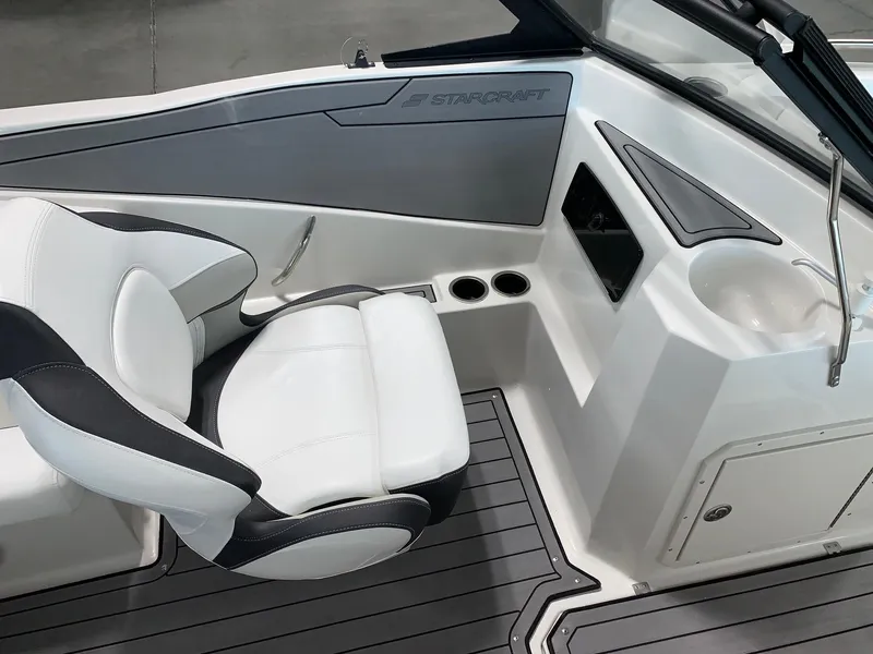 Slide: The Image of 2024 Starcraft SVX 210 boat interior with white and black seating, cup holders, and storage. - 6