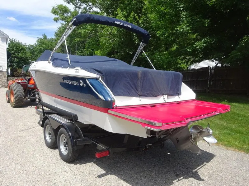 Slide: The Image of 2015 Four Winns Sundowner 235 boat on trailer with cover, parked outdoors. - 2