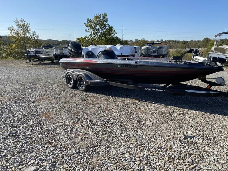The Image of 2015 Triton 21TRX boat on a trailer in a gravel lot. - 1