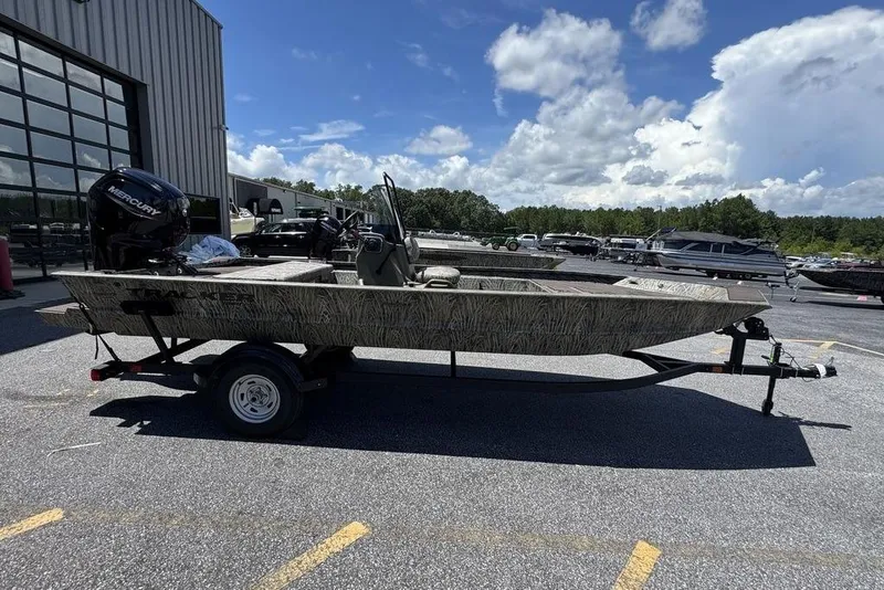Slide: The Image of 2024 Tracker GRIZZLY® 1860 CC boat on trailer, parked outdoors under a cloudy sky. - 7