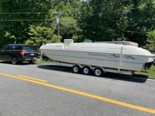 Slide: The Image of 1998 Bayliner 2659 Rendezvous boat on trailer, towed by a black SUV on a sunny day. - 5