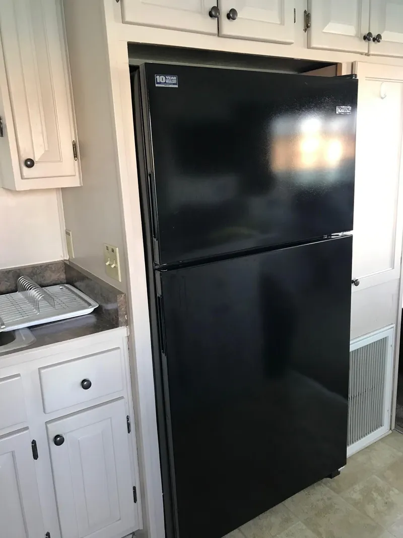 Slide: The Image of Black refrigerator in a 1996 Stardust Cruisers kitchen with white cabinets. - 13
