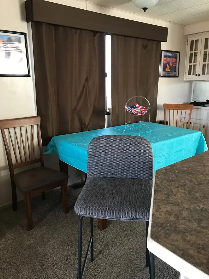 Slide: The Image of Dining area in a 1996 Stardust Cruiser with a turquoise tablecloth and brown curtains. - 15