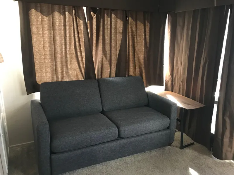 Slide: The Image of Dark gray sofa in a cozy room with brown curtains and a small side table. - 16