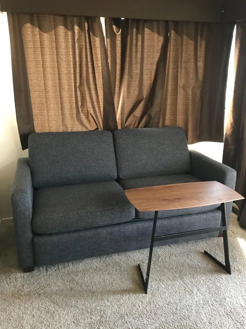 Slide: The Image of Gray sofa with a wooden side table in front of brown curtains. - 17