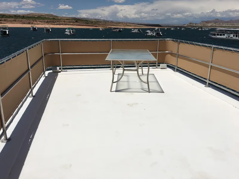 Slide: The Image of Top deck of a 1996 Stardust Cruisers houseboat with a table, overlooking a lake. - 8