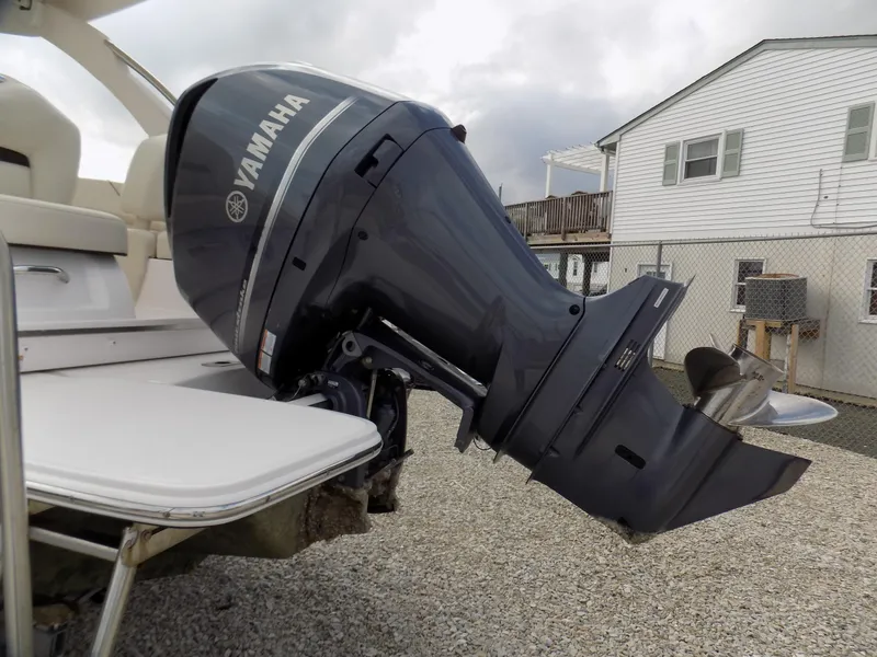 Slide: The Image of 2021 Regal LX6 boat with Yamaha outboard motor, parked on gravel near a house. - 17