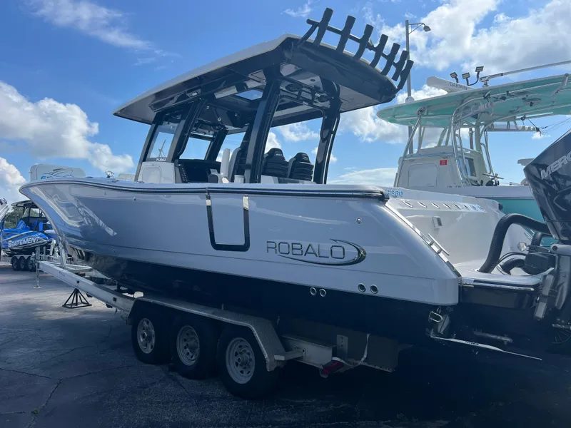 Slide: The Image of 2024 Robalo R360 boat on trailer under blue sky. - 2