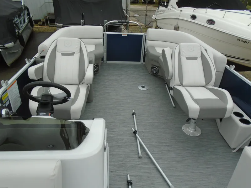 Slide: The Image of 2023 Godfrey 2286SBCX pontoon boat interior with plush seating and steering console. - 2