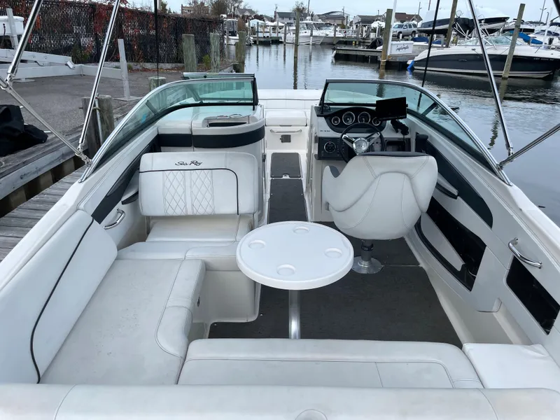 Slide: The Image of 2015 Sea Ray 240 Sundeck boat interior with seating and helm at marina. - 2