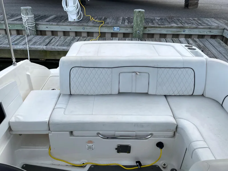Slide: The Image of 2015 Sea Ray 240 Sundeck boat interior with white cushioned seating at dock. - 8