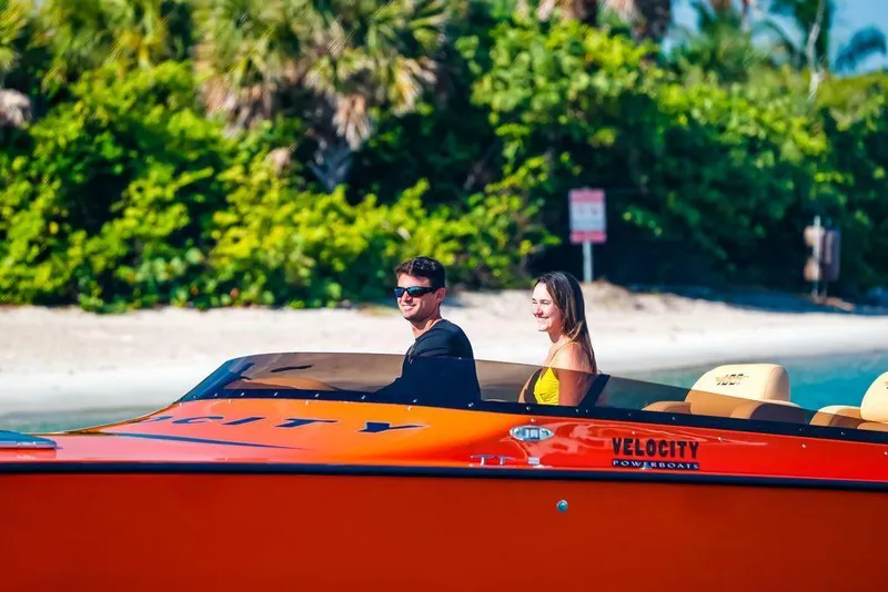 Slide: The Image of 2024 Velocity 430VRX powerboat with two people cruising near a tropical shoreline. - 9