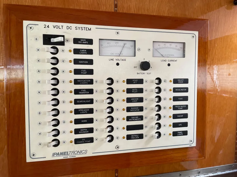 Slide: The Image of 1974 custom center cockpit 24V DC system panel with switches and gauges on wooden background. - 14