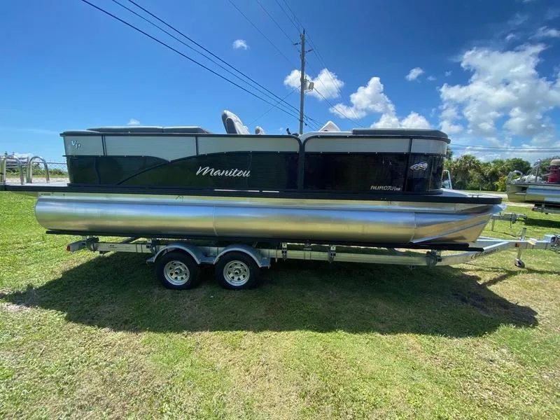 Slide: The Image of 2021 Manitou 21 AURORA LE RF VP pontoon boat on a trailer under a clear blue sky. - 4