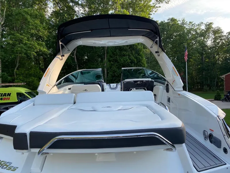 Slide: The Image of 2015 Monterey 288 Super Sport boat with sleek design, white seating, and canopy in a wooded area. - 2