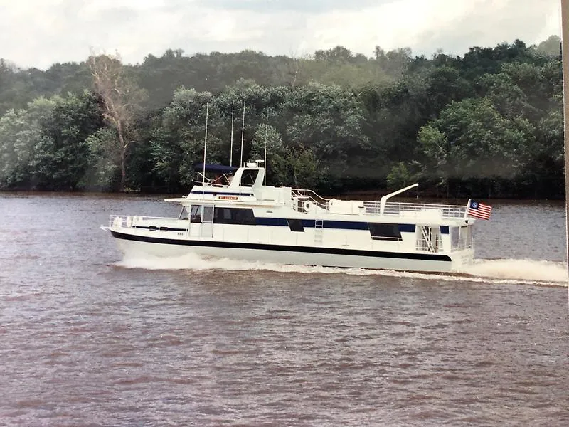 Slide: The Image of 1989 Pluckebaum 75 Coastal Cruiser yacht sailing on a river with forested background. - 2