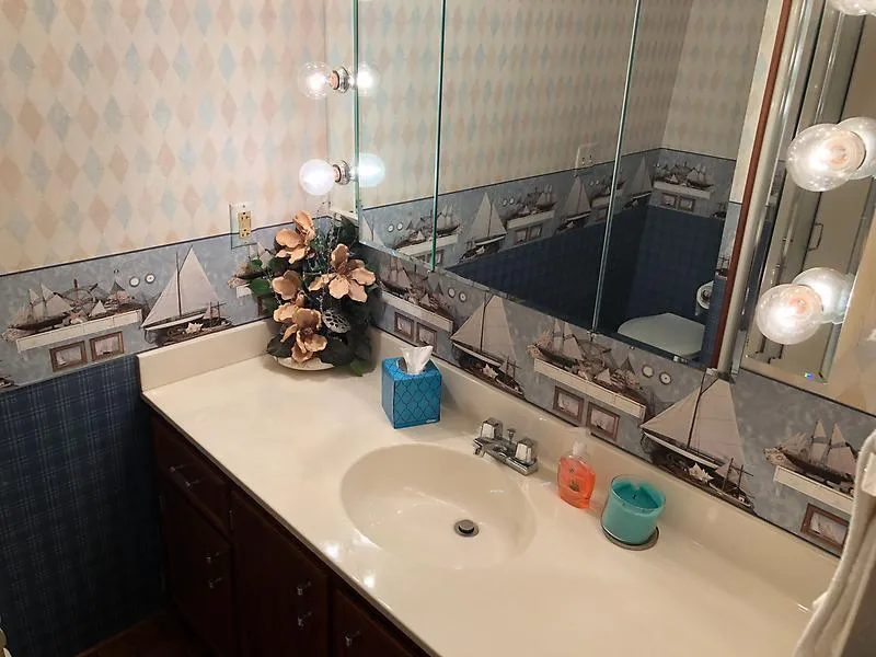 Slide: The Image of Bathroom vanity with nautical-themed wallpaper on a 1989 Pluckebaum 75 Coastal Cruiser. - 20