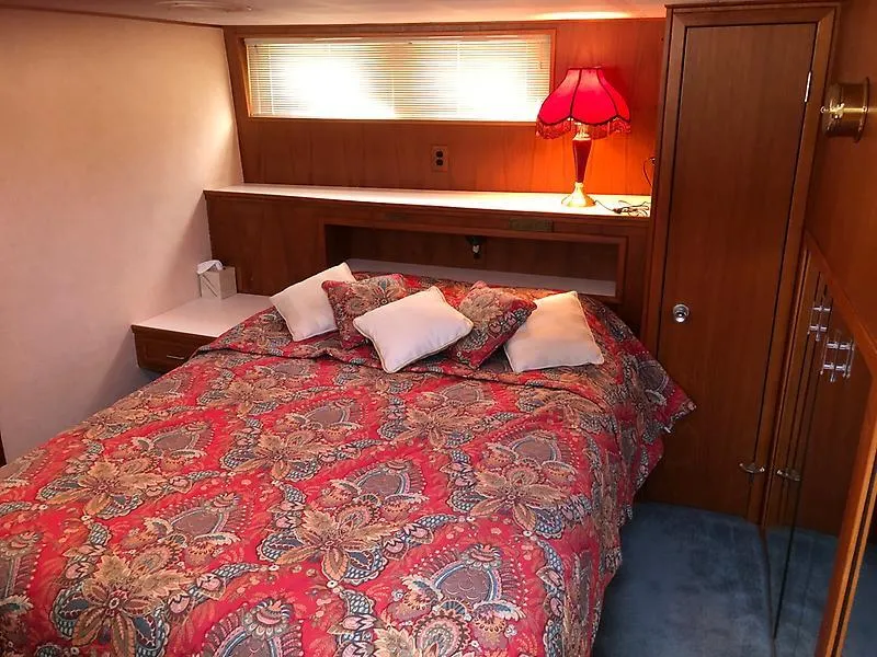 Slide: The Image of Cozy bedroom in 1989 Pluckebaum 75 Coastal Cruiser with red patterned bedding and wooden decor. - 6
