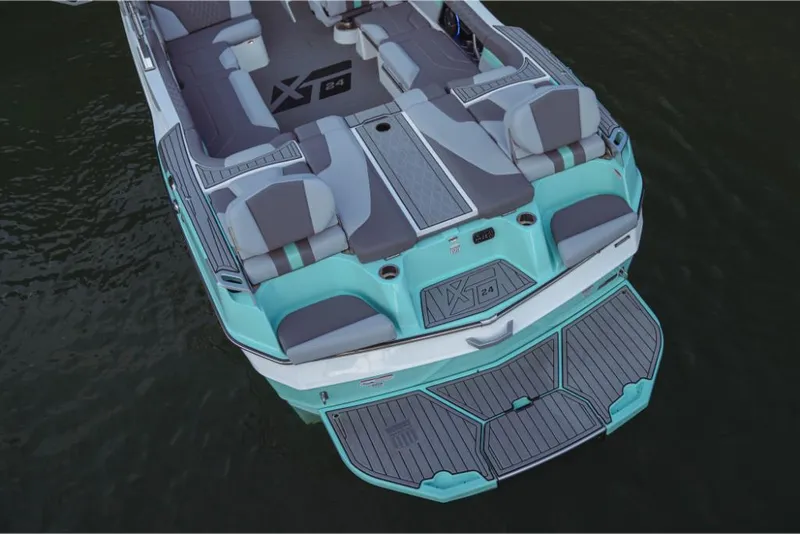 Slide: The Image of 2023 MasterCraft XT24 boat, rear view, teal and gray seating, on water. - 14