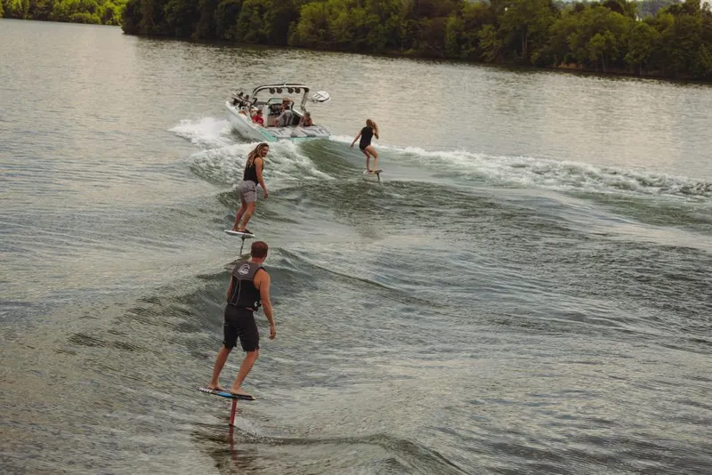 Slide: The Image of People wakeboarding behind a 2023 MasterCraft XT24 boat on a lake. - 25