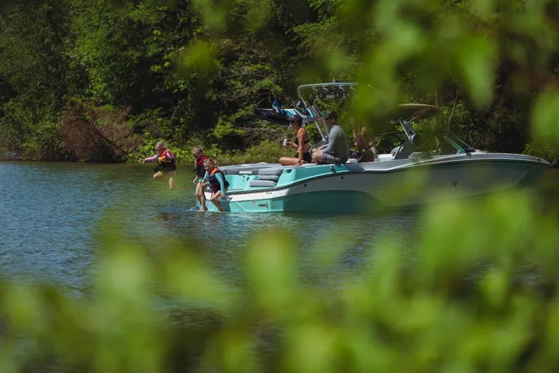 Slide: The Image of 2023 MasterCraft XT24 boat on a lake with people enjoying water activities. - 4