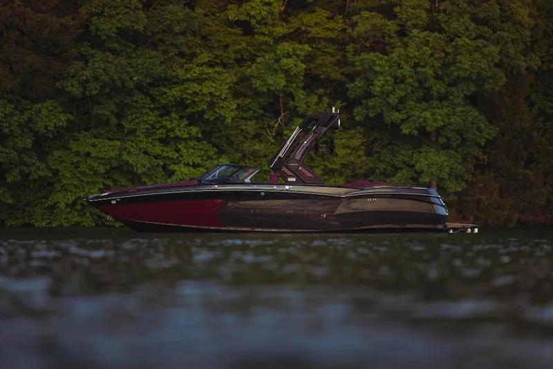 Slide: The Image of 2023 MasterCraft XStar S boat on a lake with a forested background. - 0