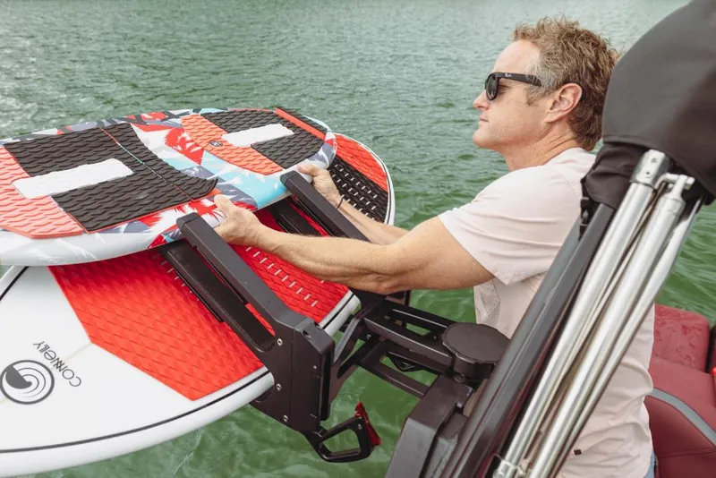 Slide: The Image of Man securing surfboards on 2023 MasterCraft XStar S boat. - 13