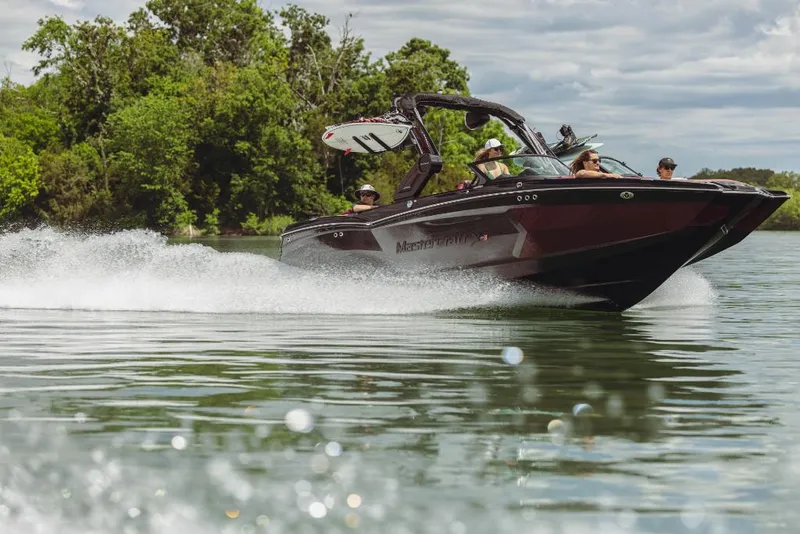 Slide: The Image of 2023 MasterCraft XStar S speedboat cruising on a lake with passengers. - 4