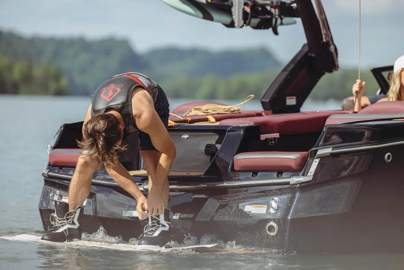 Slide: The Image of 2023 MasterCraft XStar S boat with wakeboarder preparing on the platform. - 6