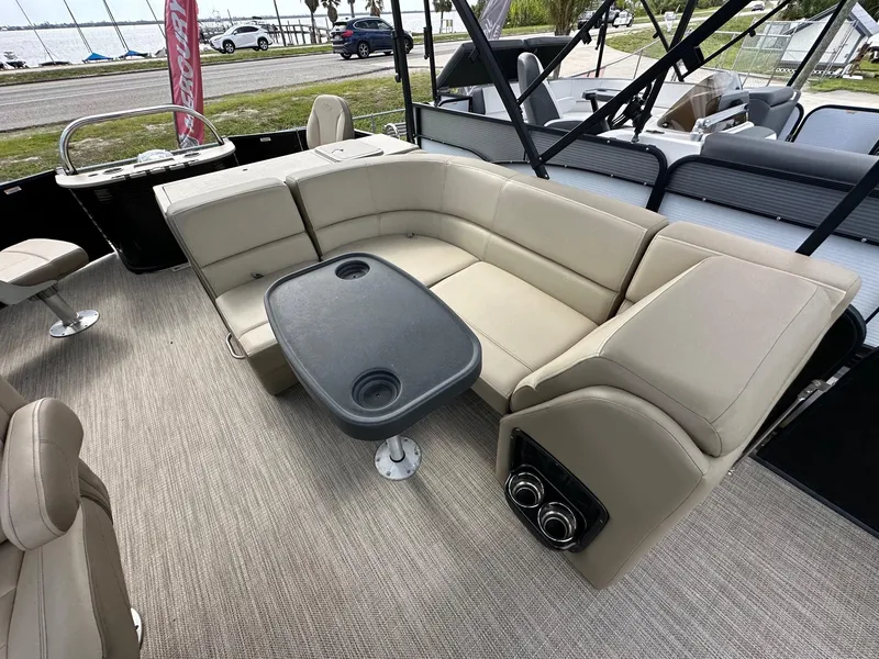 Slide: The Image of 2022 Manitou 20 Aurora Angler LE Standard pontoon boat interior with beige seating and table. - 11