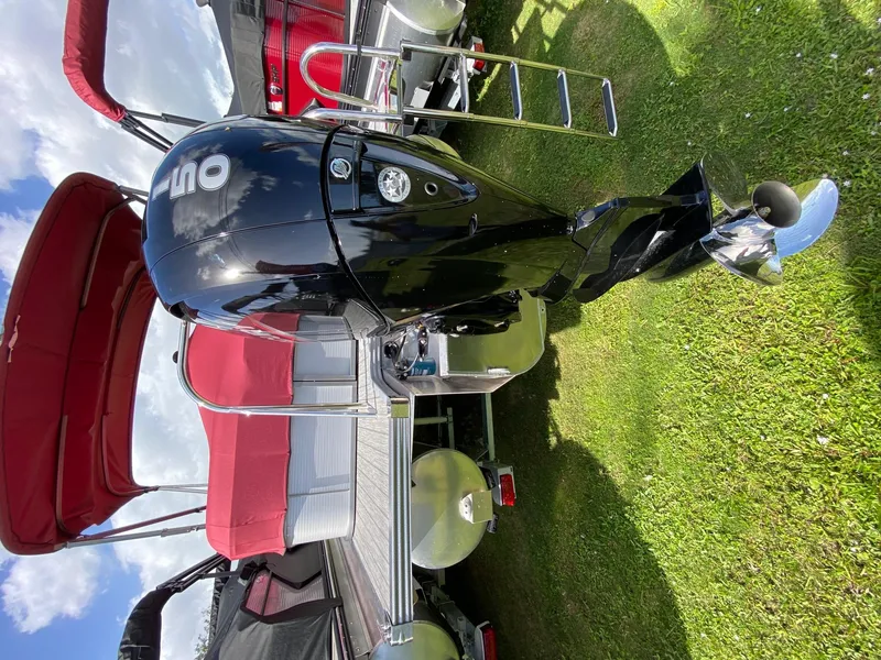 Slide: The Image of 2021 Manitou Oasis pontoon boat with outboard motor and red canopy. - 3