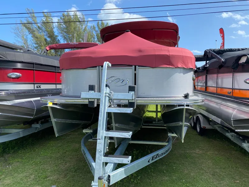 Slide: The Image of 2021 Manitou Oasis pontoon boat with red cover on trailer. - 4