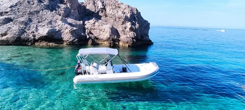 The Image of 2024 ZAR Mini RIB 16 boat anchored near rocky shore in clear blue water. - 0