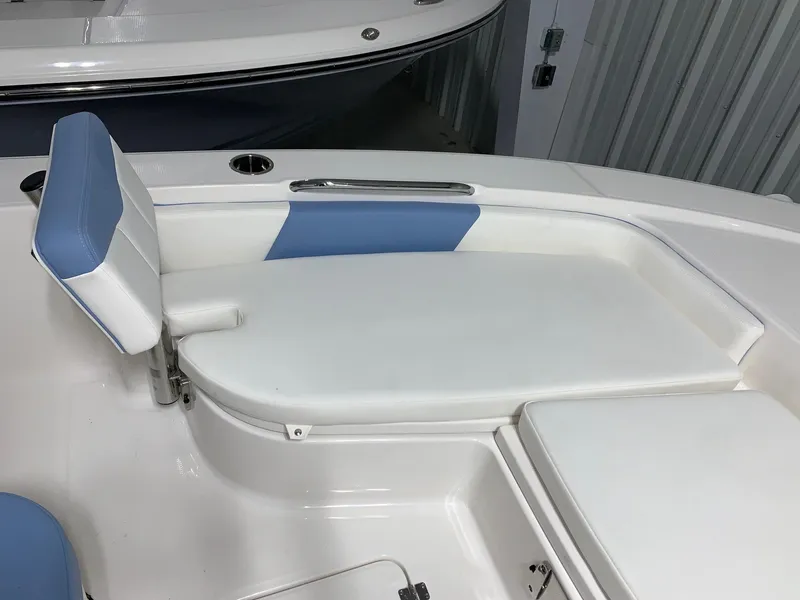 Slide: The Image of 2024 Robalo 226 Cayman boat interior seating with white and blue cushions. - 16