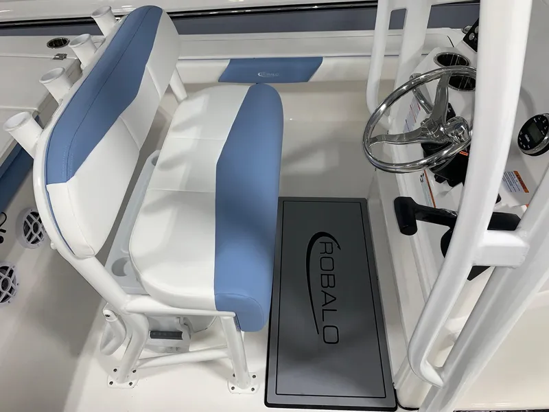 Slide: The Image of 2024 Robalo 226 Cayman boat interior with blue and white seating and steering console. - 6