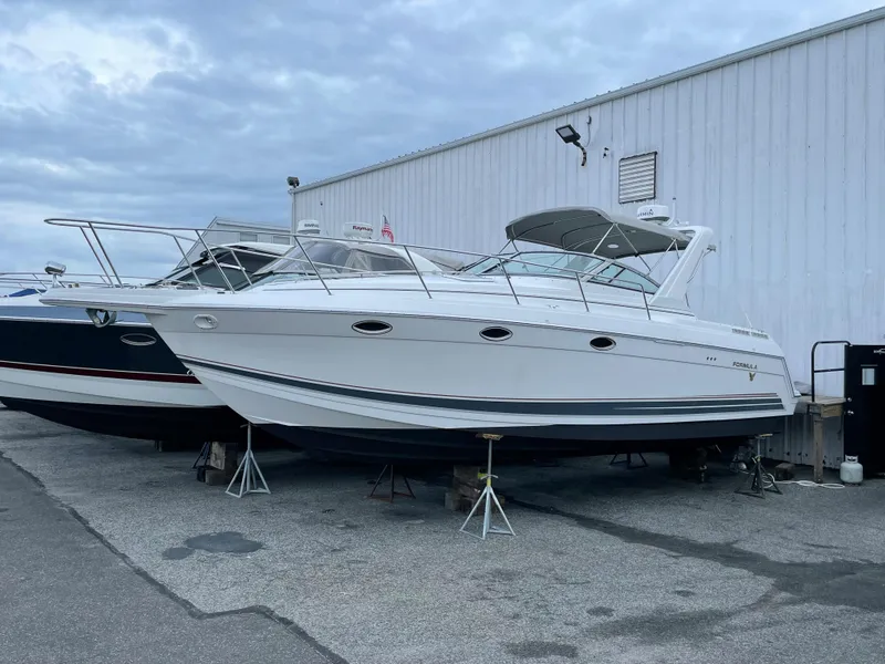 The Image of 2002 Formula 31 PC boat on stands near a white building. - 0