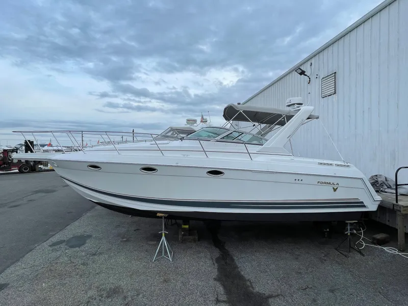 Slide: The Image of 2002 Formula 31 PC boat docked near a white building under a cloudy sky. - 1