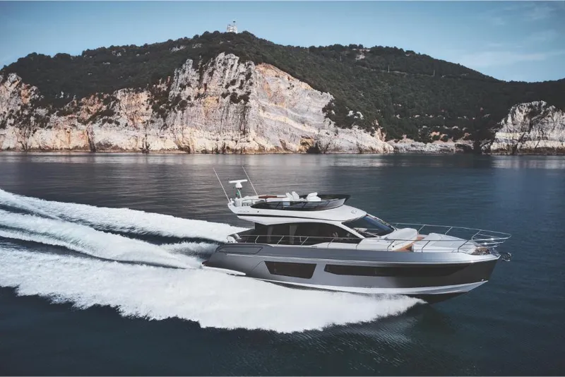 Slide: The Image of 2023 Azimut 53 yacht cruising near rocky coastline. - 2
