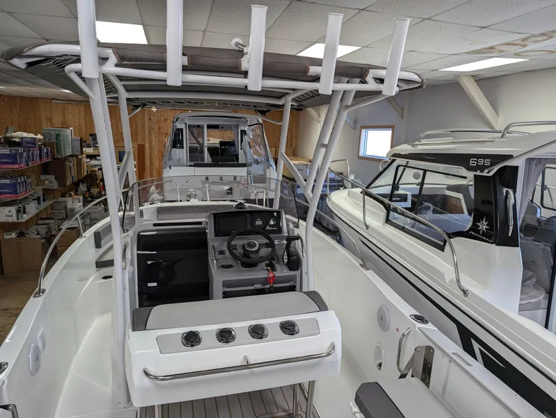 Slide: The Image of 2023 Jeanneau Leader 6.5 S3 CC boat interior, showcasing helm and seating area in showroom. - 10