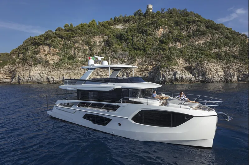 Slide: The Image of 2025 Absolute Navetta 64 yacht cruising near rocky coastline. - 0