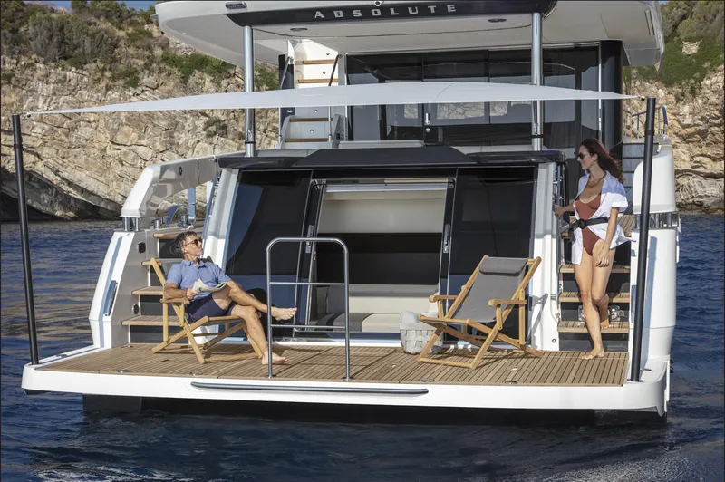 Slide: The Image of 2025 Absolute Navetta 64 yacht with people relaxing on deck in scenic waters. - 3