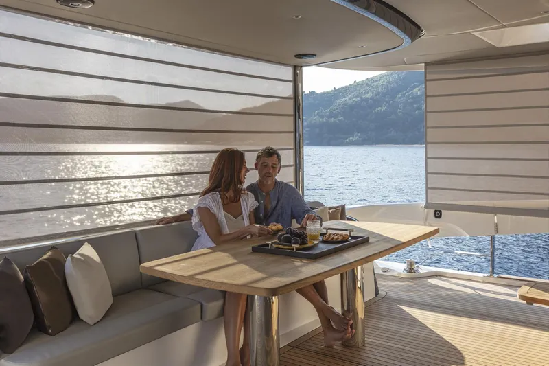 Slide: The Image of Couple dining on Absolute Navetta 64 yacht, 2025 model, with scenic ocean view. - 9