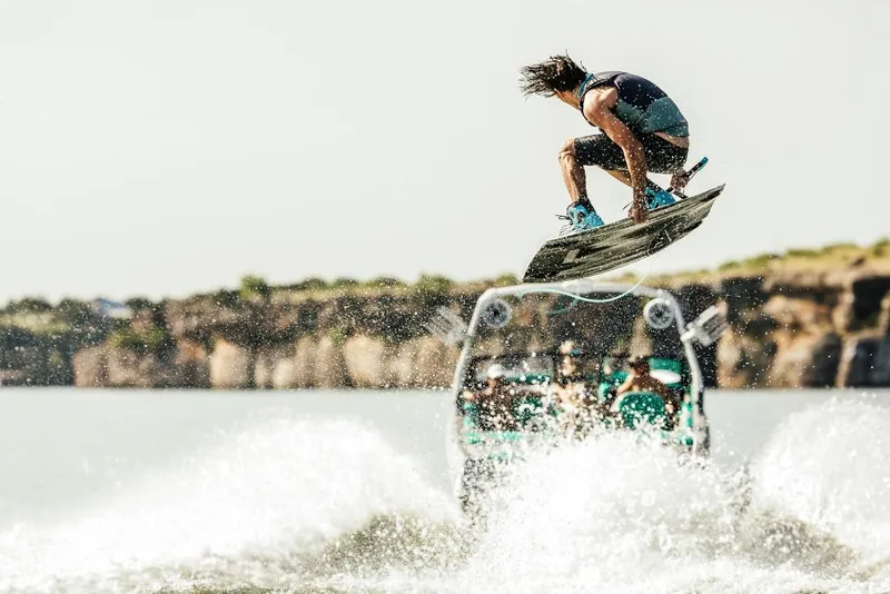 Slide: The Image of Wakeboarder performing a jump behind a 2023 Tigé 24RZX boat. - 15