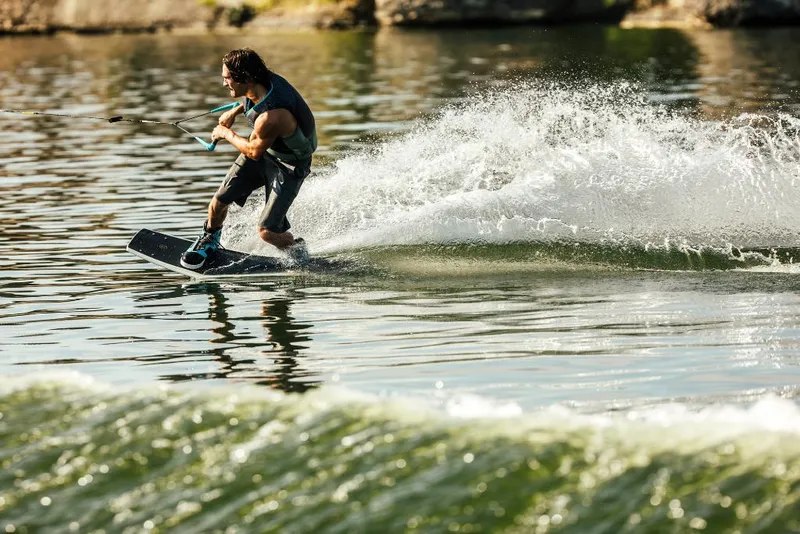 Slide: The Image of Wakeboarder riding waves behind 2023 Tigé 24RZX boat on a sunny day. - 16